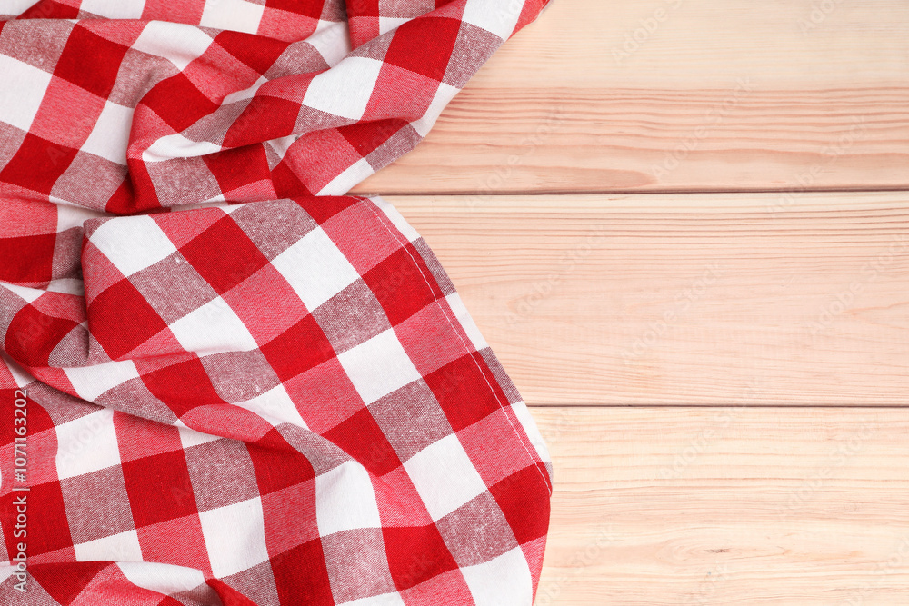 Obraz premium Crumpled tablecloth with checkered pattern on light wooden table, space for text