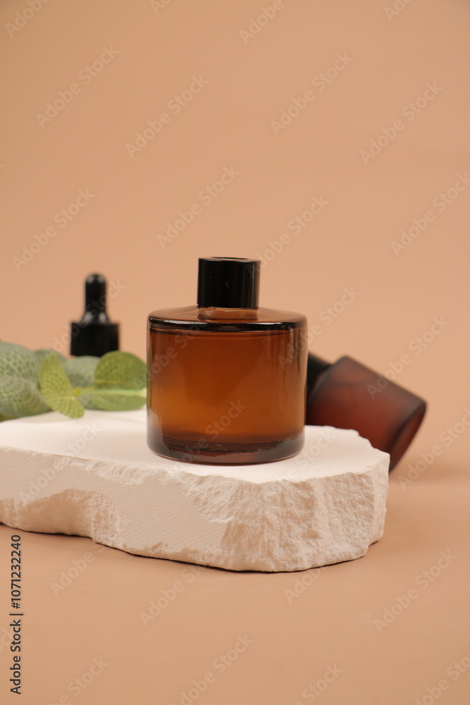 Amber Glass Cosmetic Jar with Greenery and Natural Stone on Beige Background Amber Glass Cosmetic Jar with Greenery and Natural Stone on Beige Background