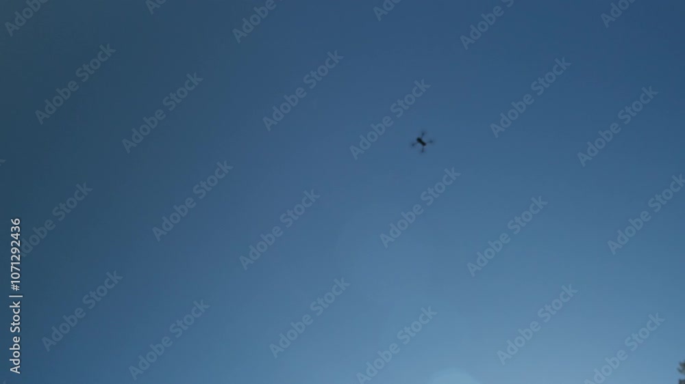Defocused cinematic shot of drone flying in the blue sky. Blurred motion of quadcopter in distance, view from below. Defocused cinematic shot of drone flying in the blue sky. Blurred motion of quadcopter in distance, view from below.