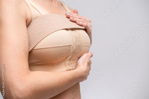 woman patient In post surgical Compression bra, implants stabilizer bra after plastic surgery medical mammoplasty, mastopexy breast enlargement, on white background