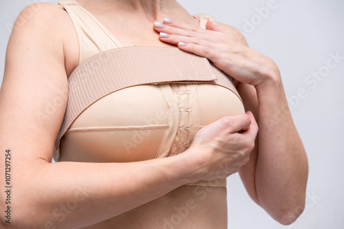 woman patient In post surgical Compression bra, implants stabilizer bra after plastic surgery medical mammoplasty, mastopexy breast enlargement, on white background