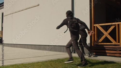 Two Armed, Masked Burglars Attempt a Break-In but Are Chased Away by a Guard Dog Protecting the Home. Concept of Home Security Pet Protection, and the Role of Guard Dogs in Deterring Criminal Activity