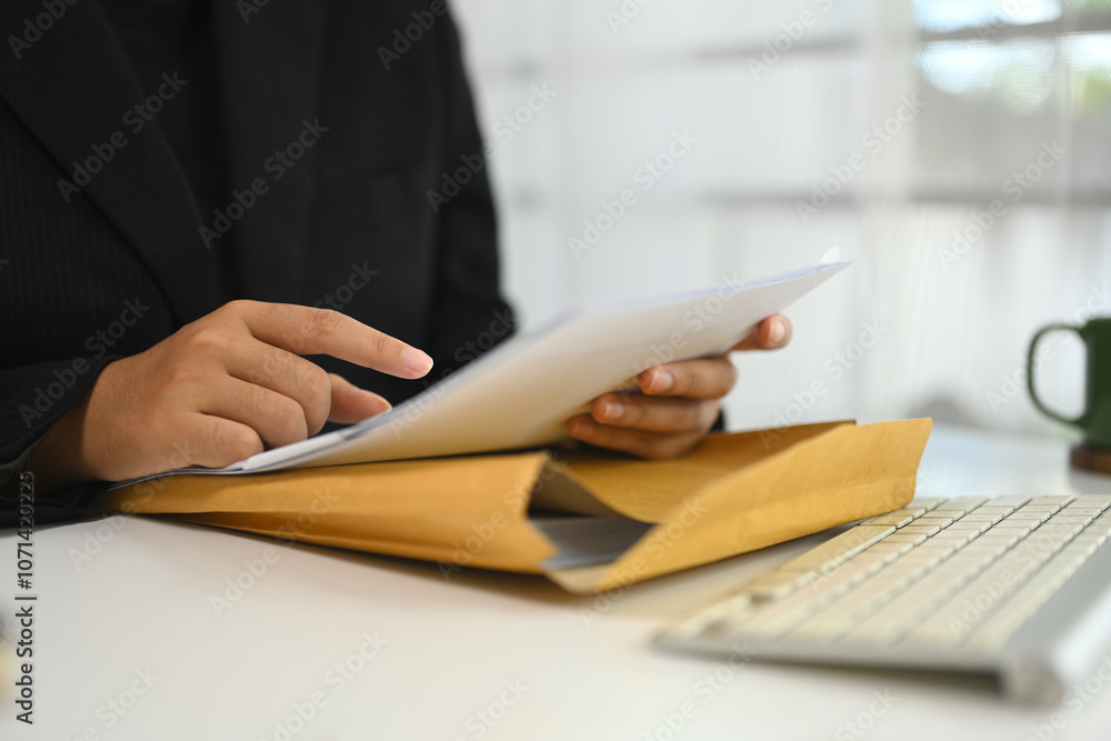 Fototapeta premium Cropped shot businesswoman examining important documents at her desk