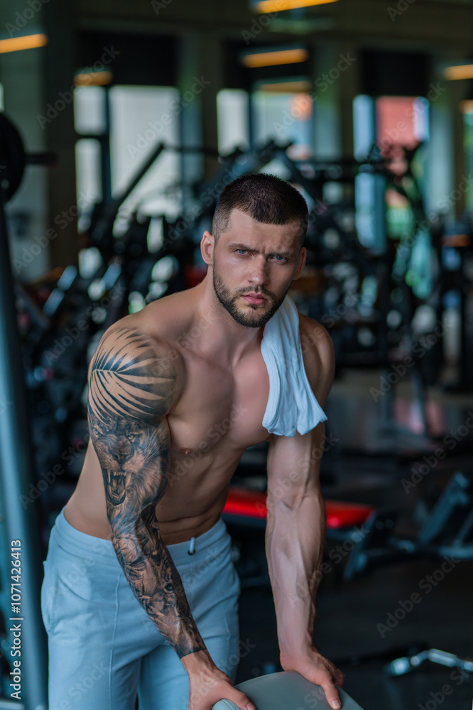 Fototapeta premium Motivated male athlete does exercise, bodybuilding workout at gym. Strong muscular man has fitness workout. Sport and healthy lifestyle concept. Muscular man workout in gym doing exercises with