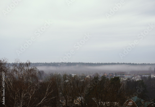 White fog spreads across the valley and covers the village photo