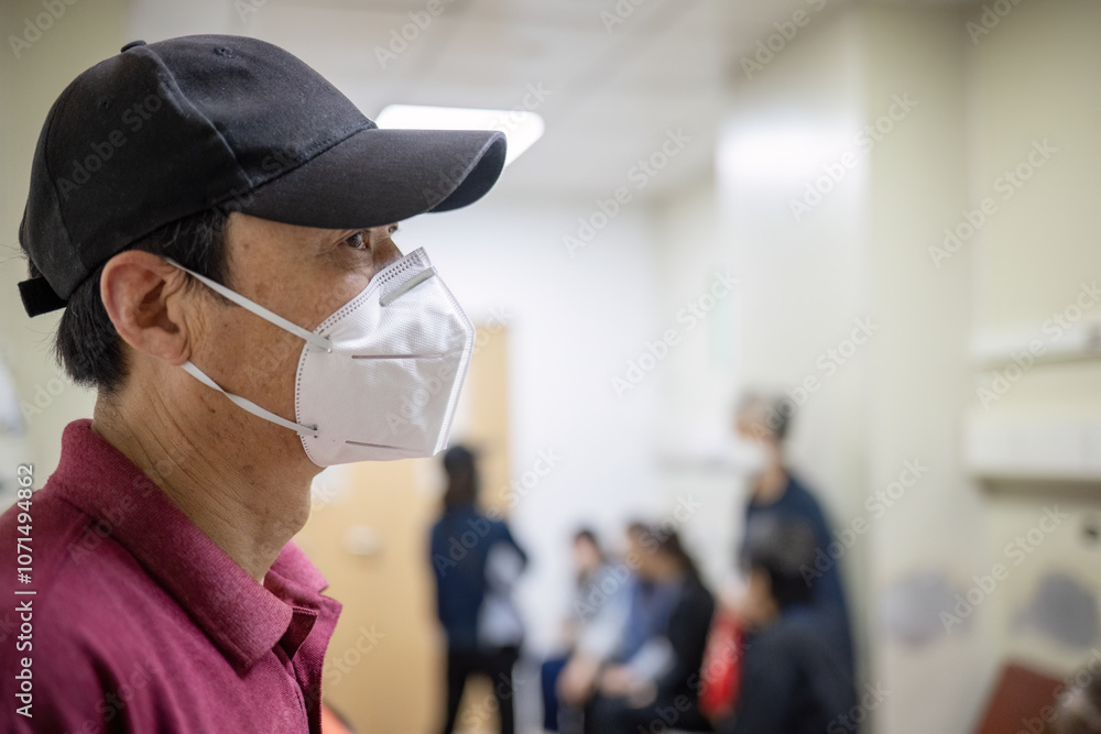 Man wearing a facemask at the hospital waiting room. Unrecognizable people in a corridor in the hospital.