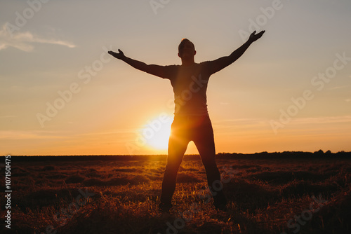 Man with Arms Outstretched in Field at Sunset