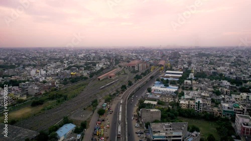 aerial drone shot following metro train on elevated track going to station as it passes between buildings, houses, homes in the densely populated city of jaipur, lucknow, hyderabad, cochin photo