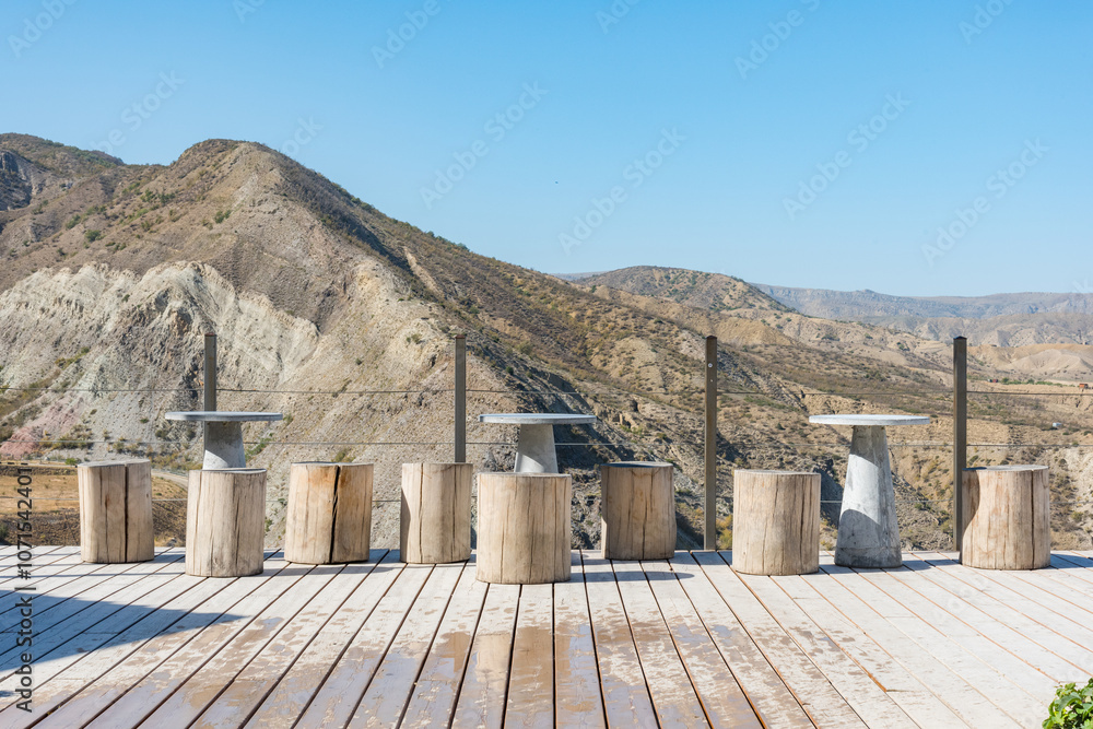 outdoor cafe in the mountains with stone tables and chairs made of wooden stumps against the background of the mountains outdoor cafe in the mountains with stone tables and chairs made of wooden stumps against the background of the mountains