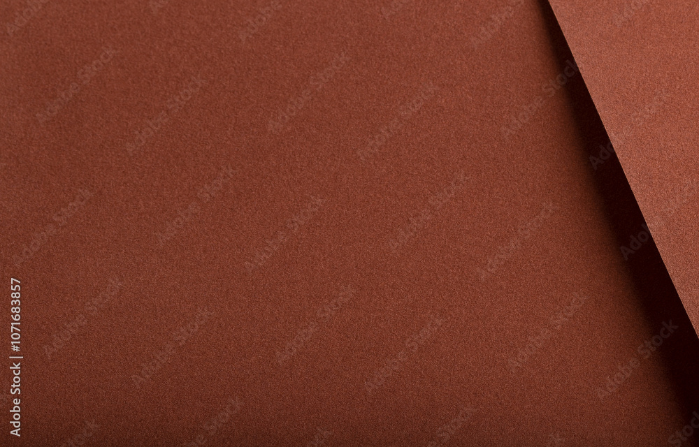 Fototapeta premium Designer paper background with a velvety, matte texture in warm, earthy hues like terracotta, ochre, and cinnamon. This rich, plush surface has a subtle gradient and grainy,