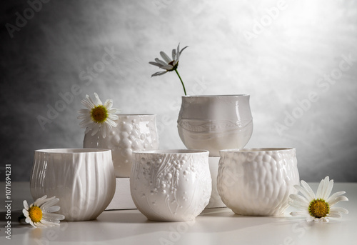 Porcelain white cups with chamomile flowers on a light table