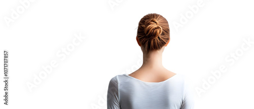 A woman facing away from the camera, her hair neatly pulled back into a bun, stands before a white wall photo