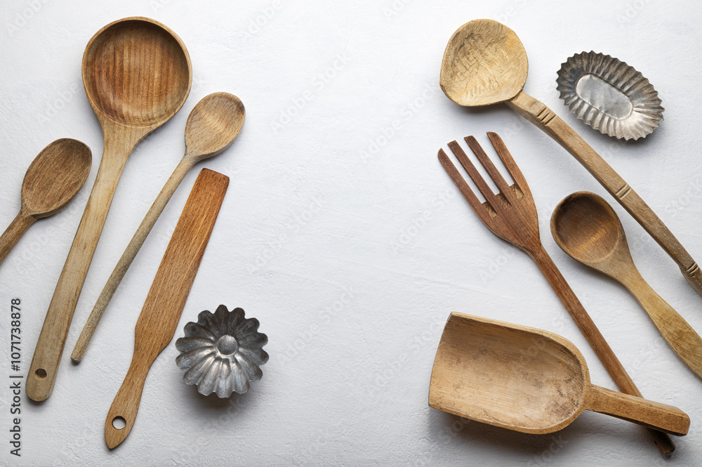 Ladles and other wooden kitchen tools on white plaster background, top view, space for text.