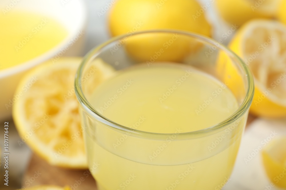 Glass of fresh lemon juice and squeezed fruits on table, closeup Glass of fresh lemon juice and squeezed fruits on table, closeup