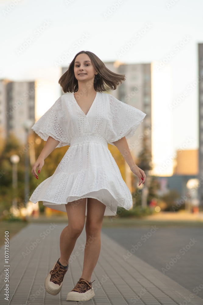 Portrait of a young beautiful girl in a white dress outdoors in an urban environment. Portrait of a young beautiful girl in a white dress outdoors in an urban environment.