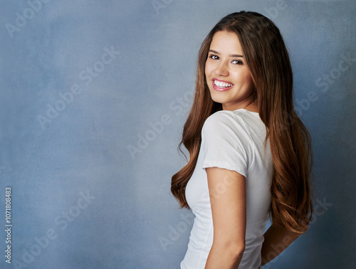 Happy woman, portrait and beauty with hair on space for style in casual clothing on a blue studio background. Young brunette, female person or attractive model with smile or expression on mockup