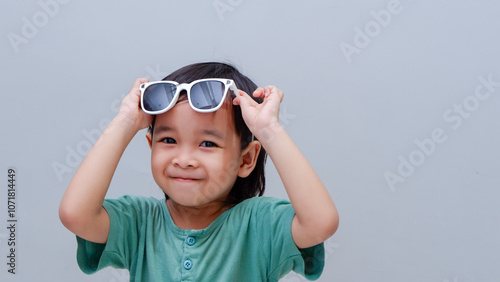 cute young Asian toddler pose holding eyeglasses 