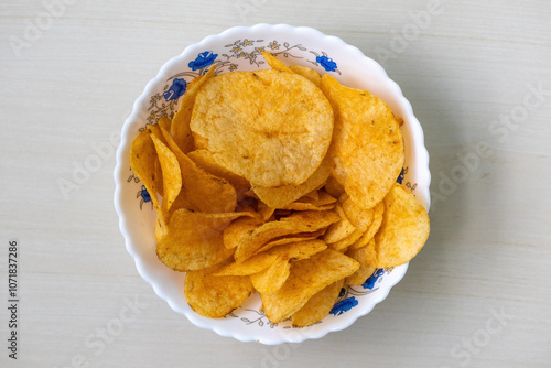 Slika na platnu A bowl of crispy potato chips on light wooden Surface