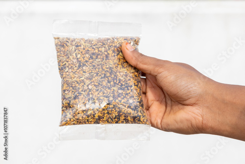 Female hand holds a packet of Panch phoron. Panch phodan is a blend of five aromatic spices, commonly used in the cuisines of Eastern India and Bangladesh. It is also called Pancha phutana. photo