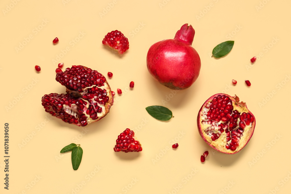 Fresh ripe pomegranates with seeds and leaves on yellow background Fresh ripe pomegranates with seeds and leaves on yellow background