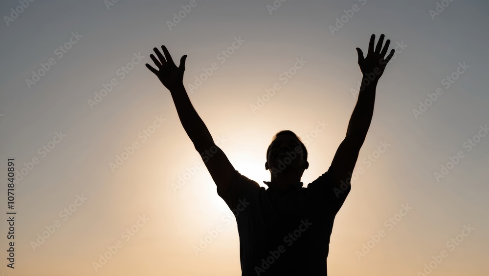 Silhouette of a person with raised hands against a sunset sky, expressing joy and freedom in an outdoor setting