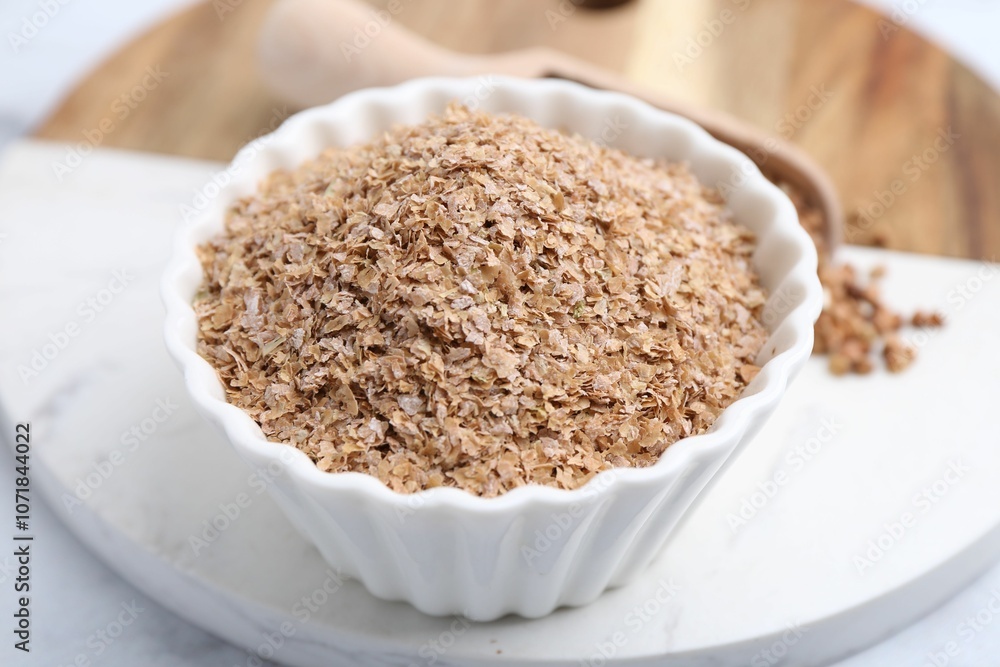 Buckwheat bran in bowl on white table, closeup Buckwheat bran in bowl on white table, closeup