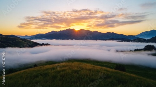 Sunrise over a valley with fog, clouds, and mountains.