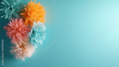 An array of vibrant, fluffy pom-poms in pink, orange, and blue arranged on a bright turquoise background, creating a lively and cheerful visual effect. photo