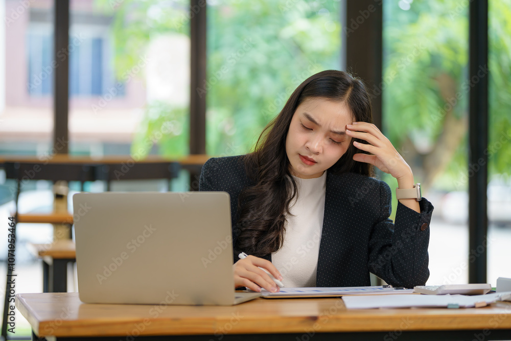 Beautiful Asian businesswoman using a laptop working in an office and depressed. Beautiful Asian businesswoman using a laptop working in an office and depressed.