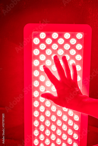 Closeup of hand touching Red Light Therapy Panel LEDs