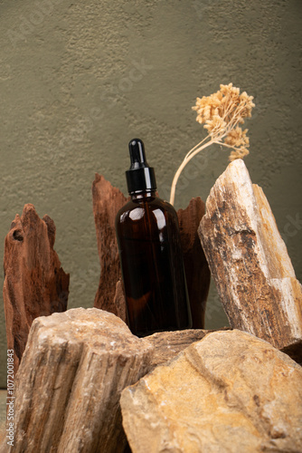 Amber Glass Dropper Bottle on Rustic Stone and Wood Background for Skincare and Aromatherapy photo