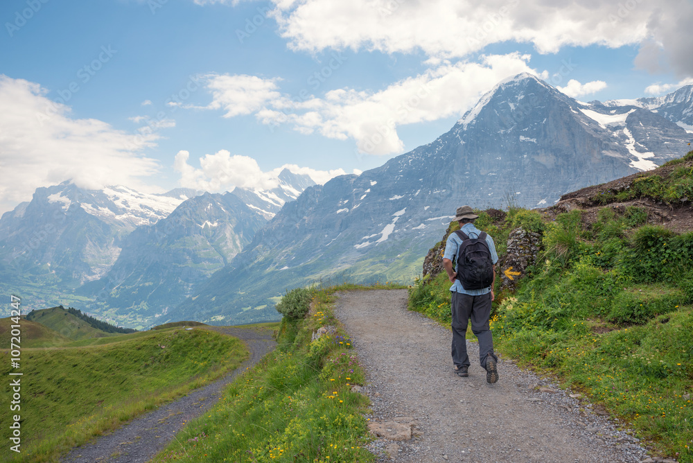 backpacker at hiking route from Mannlichen mountain to Kleine Scheidegg, Eiger north face in front. backpacker at hiking route from Mannlichen mountain to Kleine Scheidegg, Eiger north face in front.