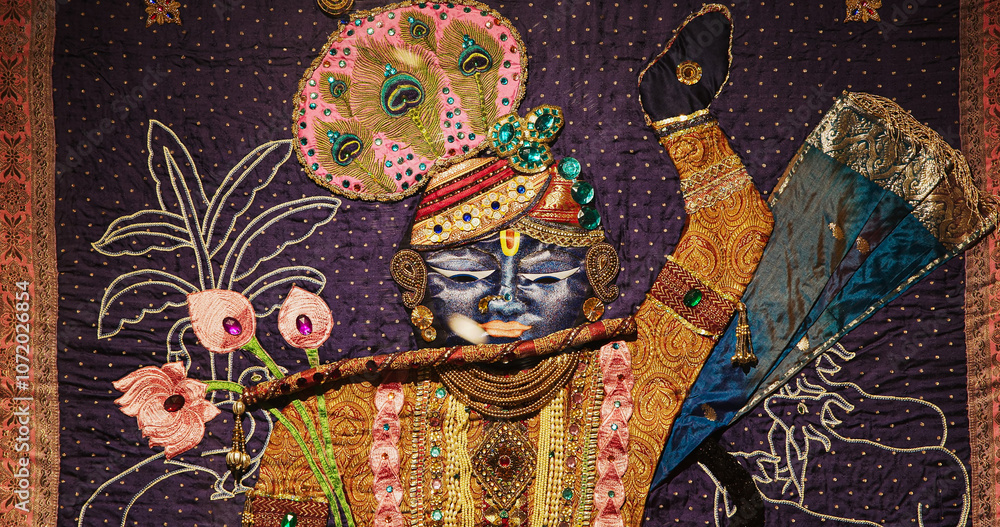 Naklejka premium Close-up View On Image Of Krishna Made From Colorful Fabrics And Embroidery With Sparkling Beads. Worship Of God Krishna. Krishna Is Major Deity In Hinduism. He Is God Of Protection, Love, Compassion