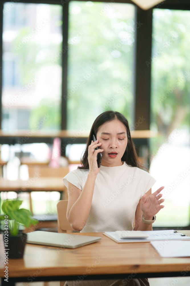 Fototapeta premium Asian business woman uses a smartphone to talk and give advice to customers.