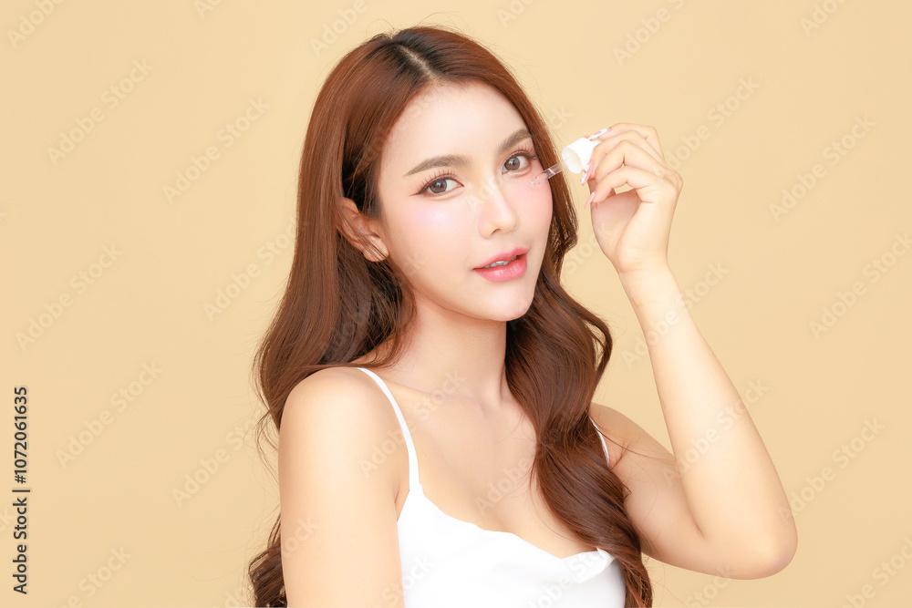 Beautiful young Asian woman model long hair using dropper for apply serum on face clean fresh skin on isolated beige background. Cute girl portrait, Facial treatment, Body care, Beauty and Spa. Beautiful young Asian woman model long hair using dropper for apply serum on face clean fresh skin on isolated beige background. Cute girl portrait, Facial treatment, Body care, Beauty and Spa.