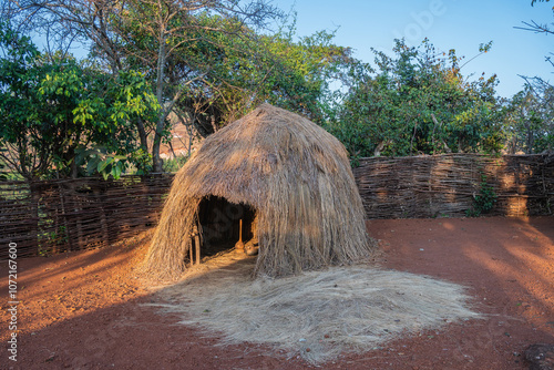 A log hut is located in the middle of a dusty dirt field, Gishora, Burundi