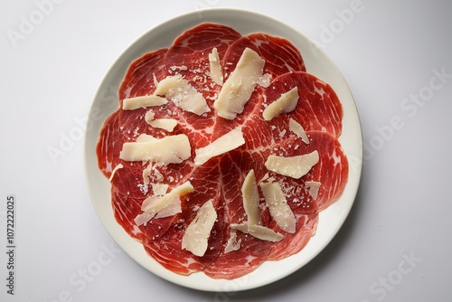 veal carpaccio with shaved parmesan cheese on a white plate