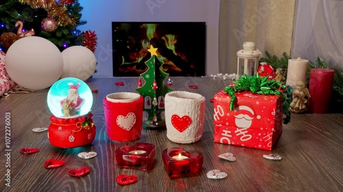 Love, hearts. Glass ball. Mugs with knitted covers. Christmas and New Year Gift Under the Tree with Garland and Ornaments. Festive Fireplace with Christmas Decor Creating a Cozy Holiday Atmosphere.