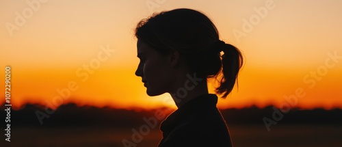 Silhouette of a person against an orange sunset sky