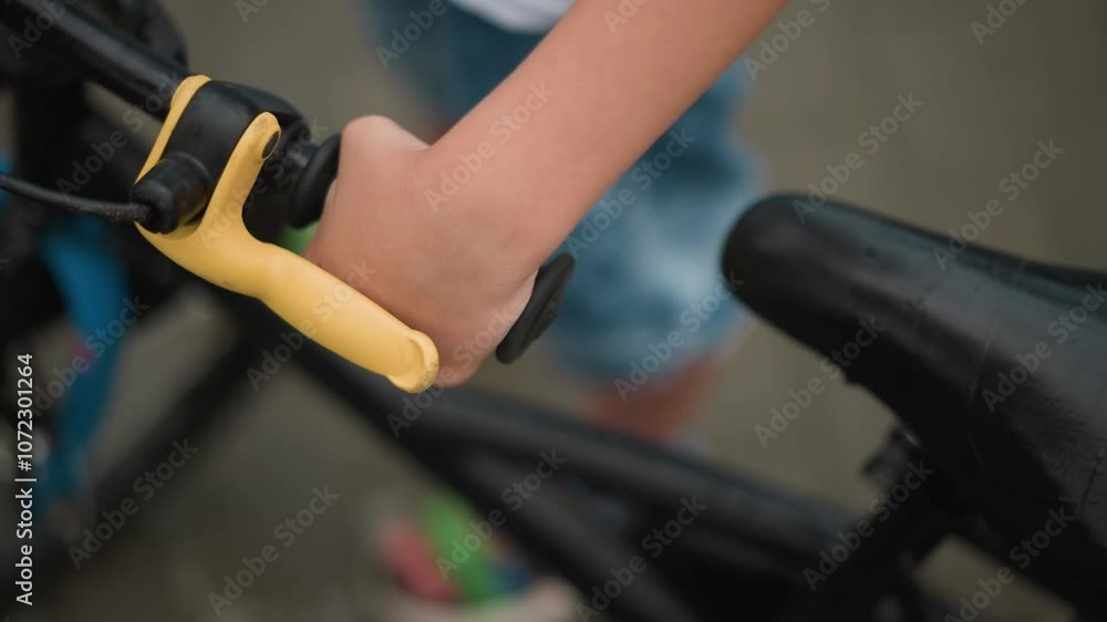 A close-up of a young boy's hand gripping the handlebar of a bicycle A close-up of a young boy's hand gripping the handlebar of a bicycle