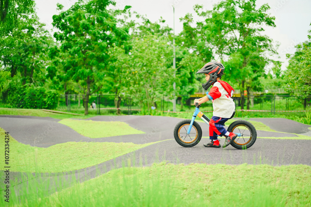 4 years old boy in safety helmeriding balance bike at summer park green trees enjoy happy childhood. .Kids on bicycle in sunny park. Sport for kids.