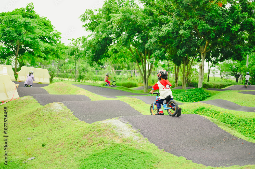 4 years old boy in safety helmeriding balance bike at summer park green trees enjoy happy childhood. .Kids on bicycle in sunny park. Sport for kids. 4 years old boy in safety helmeriding balance bike at summer park green trees enjoy happy childhood. .Kids on bicycle in sunny park. Sport for kids.