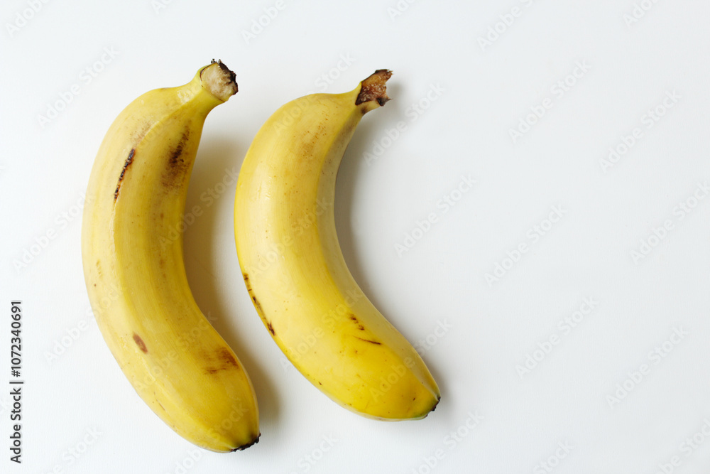 Two bananas on white background with copy space. Healthy, organic, vitamin rich ingredient for vegan diet meals. Sweet and nourishing tropical fruits. Two bananas on white background with copy space. Healthy, organic, vitamin rich ingredient for vegan diet meals. Sweet and nourishing tropical fruits.