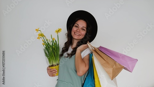 The girl happily makes purchases with packages and flowers. White background