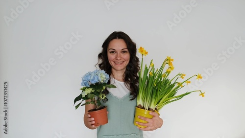 Beautiful young woman florist with flowers on white background smiling at camera