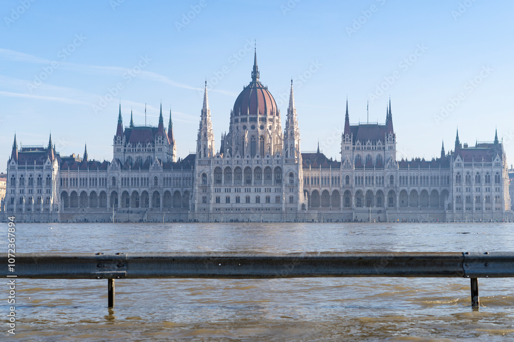 Fototapeta premium The neo-Gothic building of the Hungarian legislature, the Parliament with the river Danube flooding the quays in the foreground