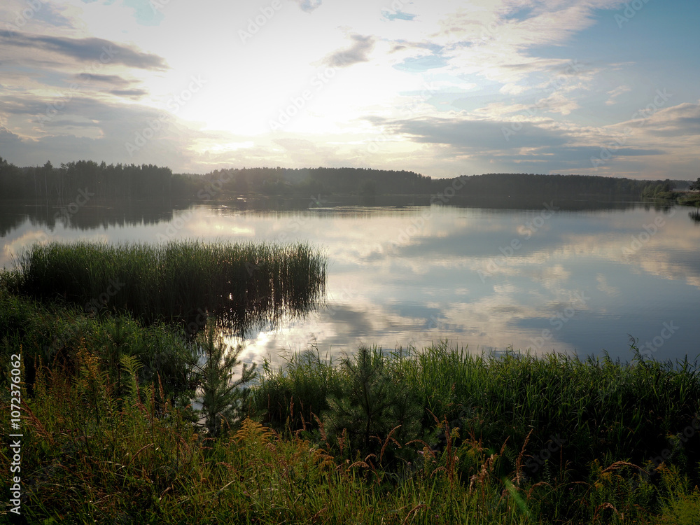 Sunset on the lake. Beautiful summer landscape with lake and trees.