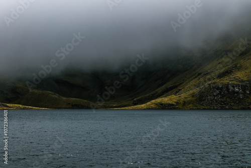 Misty lake surrounded by lush hills in a remote mountainous area during early morning hours. photo