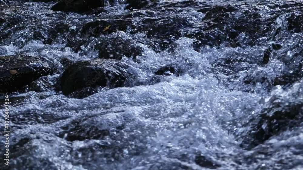 Rushing water flowing over rocks in a river. Concept: River, waterfall, torrent. Rushing water flowing over rocks in a river. Concept: River, waterfall, torrent.