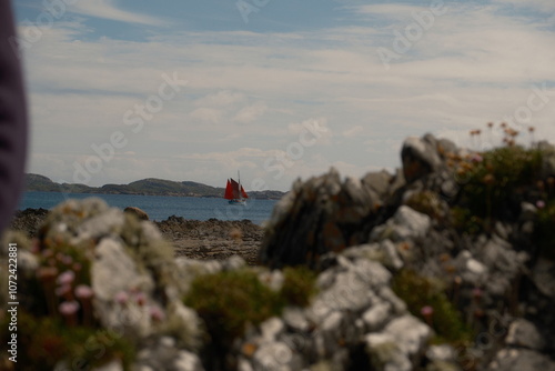 sail boat on loch sea through shore rocks